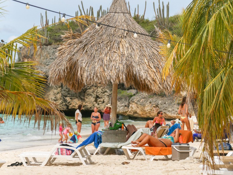 Mensen ontspannen op het palmenstrand van Cas Abou, Curaçao