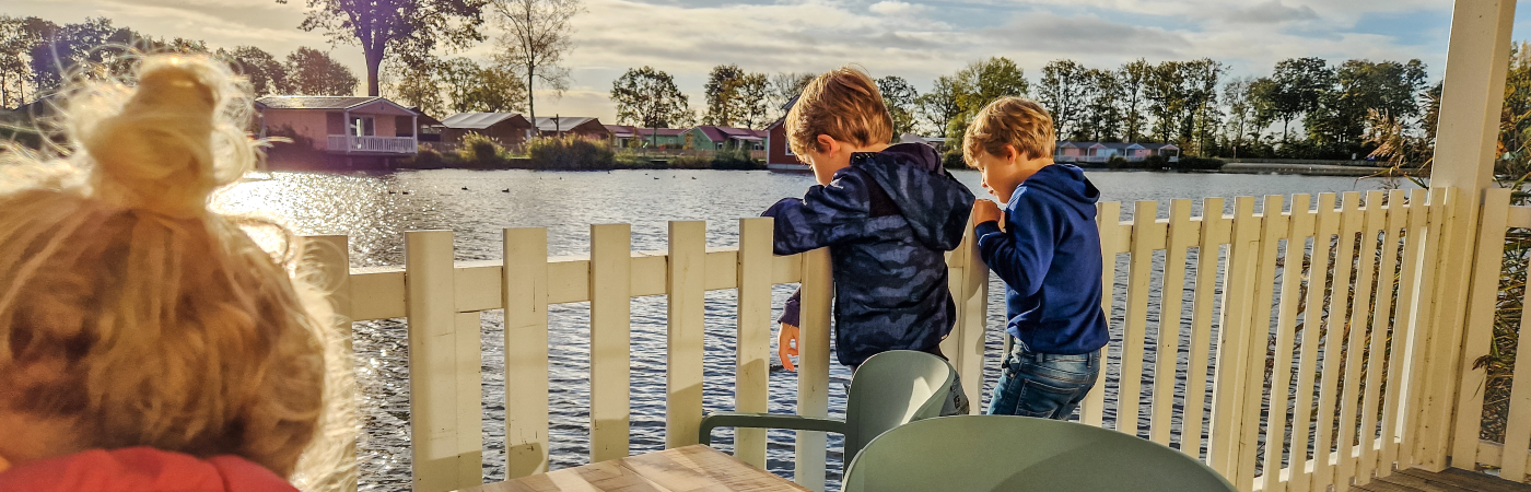 De kinderen kijken uit over het water langs ons huisje op vakantiepark Molenwaard