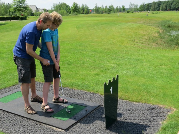 Patrick helpt Zeb voor zijn eerste afslag op de golfbaan