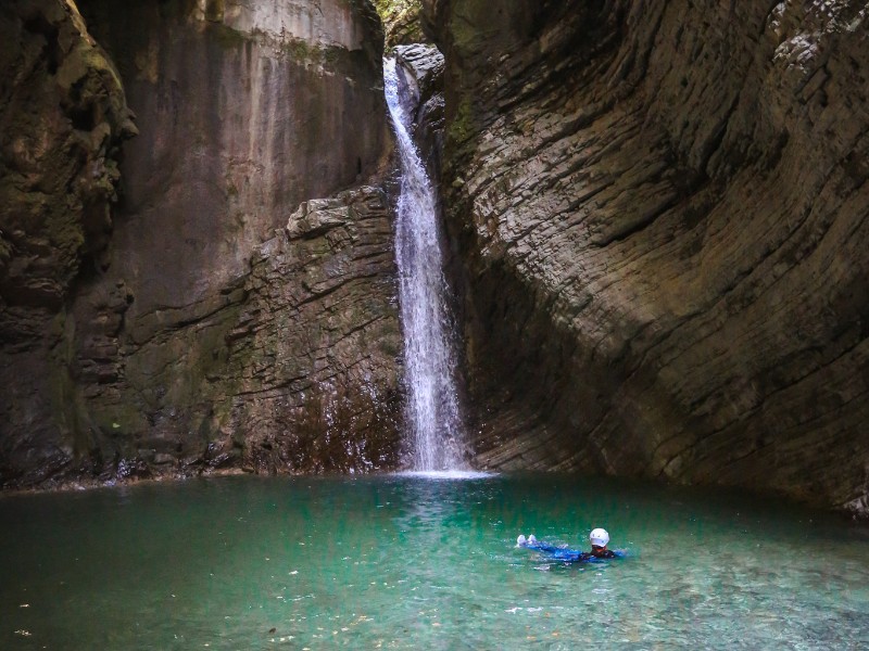 Een man in het water bij de Kozjak waterval na een duik tijdens het Canyoning