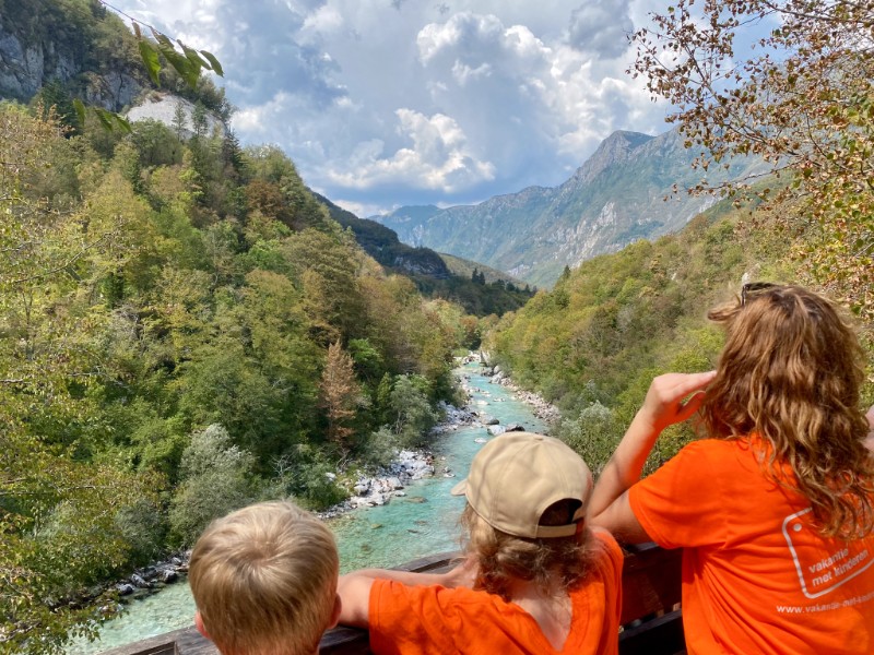 Elisabeth en haar kinderen kijken uit over de helderblauwe Soca rivier in Slovenië